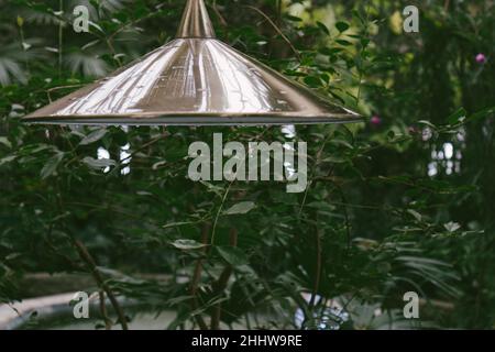 Elektrische Laterne aus Bronze im grünen Garten. Taschenlampe zwischen Bäumen Stockfoto