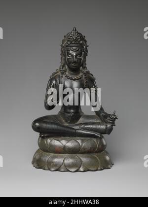 Bodhisattva Maitreya, der Buddha der Zukunft Indien des 7th. Jahrhunderts (Jammu und Kaschmir) oder Pakistan (Swat-Tal) der messianische Retter Maitreya wird durch den Kolben identifiziert, den er in seiner Unterhand hält. Er sitzt in einer yogischen Haltung auf einem Doppel-Lotuskissen und dehnt mit erhobener Hand den Gläubigen spirituellen Schutz aus, hier mit der Handfläche nach innen und nicht nach außen, wie es üblich ist. Diese Ikone hat eine hervorragend erhaltene Metalloberfläche, komplett mit silbernem Inlay an den Augen und Stirnmarkierung (Urna). Die erhöhte Ornamentik spiegelt das Bewusstsein für Gupta-Design wider. Die Figur und die Basis w Stockfoto