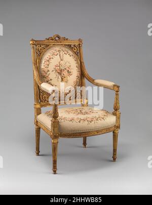Sessel (Fauteuil) ca. 1785–90 Französisch der ovale Rücken ist in einen rechteckigen Rahmen eingeschrieben und hat durchbrochene Schnitzereien aus Blumen und Blattrollen in den vier Ecken. Ein geschnitzter Lorbeerkranz überragt die Wappenschiene und vier gedrehte und geriffelte, sich verjüngende Beine stützen den Sitz. Dieser Sessel war Teil der Modellsammlung für Holzarbeiten, Verkleidungen und Sitzmöbel von Maison Leys, einem erfolgreichen Dekorationsunternehmen, das sich am Place de la Madeleine in Paris befindet. Seit 1885 wurde das Geschäft von Georges Hoentschel geleitet, der die Sammlung 1903 in einer musealen Ausstellung am Boulevard Flandri installierte Stockfoto