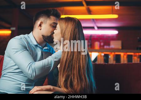 Glückliches junges Paar, das sich küsst, während es den Valentinstag im Restaurant feiert. Hände halten. Valentinstag. Wunderschönes Porträt. Stockfoto