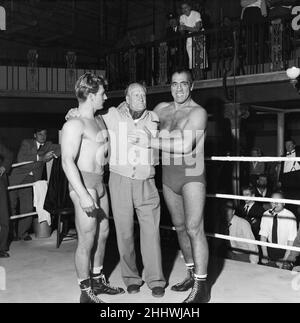 Primo Carnera, Schauspieler und professioneller Wrestler, ebenfalls ein ehemaliger Profi-Boxer, fotografierte Drehszenen für den neuen Film A Kid for Two Farthings in den Shepperton Studios, Surrey, England, 13th. September 1954. Das Set ist eine Darstellung eines Wrestling-Rings in East London. Er spielt Python Macklin, gegenüber Joe Robinson, dem World Wrestling Champion von 1951 und aktuellen Judo-Weltmeister, als Sam Heppner. Ebenfalls abgebildet, Mitte, 'Bombardier' Billy Wells, britischer und britischer Empire-Boxsieger von 1911 bis 1919. Stockfoto