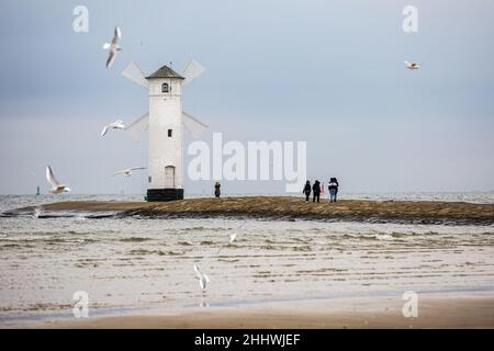 Swinoujscie, Polen. 17th. November 2021. Die Menschen sahen, wie sie um das Stawa Mlyny-Leuchtfeuer am Eingang zum Hafen von Swinoujscie gingen. Ein weißes Leuchtfeuer in Form einer Windmühle ist ein Symbol von Swinoujscie und ist Teil des offiziellen Logos der Stadt. Der Hafen von Swinoujscie ist ein polnischer Seehafen an der Ostsee. Zusammen mit dem Hafen von Stettin entsteht einer der größten Hafenkomplexe an der Ostsee. (Foto: Karol Serewis/SOPA Images/Sipa USA) Quelle: SIPA USA/Alamy Live News Stockfoto