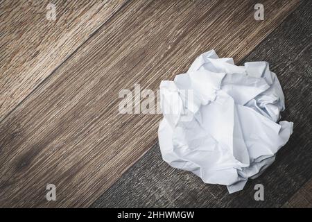 Zerknittertes und zerrissenes Papier auf dem Tisch. Zerrissenes Notizbuch. Papiermüll. Voller Korb mit Notizen. Notizblock und Bleistift auf zerknittertem Papierhintergrund. Stockfoto
