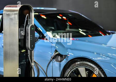 Laden eines Elektrofahrzeugs in einer Station mit Stromversorgung, die an ein Elektroauto angeschlossen ist, das aufgeladen wird Stockfoto