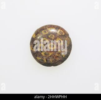 Glasmosaik Theke oder Inlay ca. 3rd. Jahrhundert n. Chr. römisch, ägyptisch Durchscheinendes Grün und opakes Gelb.Plano-konvexe Scheibe mit abgerundeter Kante.konzentrisches Muster von hohlen Kreisen in Gelb: Eine in der Mitte, umgeben von einem Ring von sechs Kreisen, und einem äußeren Ring von neun Kreisen, und zwei solide gelbe Linien, die von äußeren Kreis zu Rand auf beiden Seiten.intakt, aber leicht abgeschlagen um Rand; stumpft, braun verwittern, und schwach schillernd.. Glasmosaik-Theke oder Einlage. Römisch, ägyptisch. Ca. 3rd Jahrhundert n. Chr.. Glas. Britisch. Glas Stockfoto