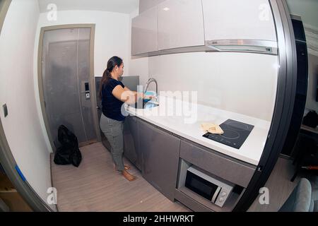 Eine asiatische weibliche Maid waschen Lumpen in der Küche Waschbecken in einem Zimmer in der Wohnung. Stockfoto