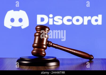 Gavel auf dem Tisch vor dem Hintergrund des Logos der sozialen Gaming-Plattform von Discord. Das Konzept des Prozesses. Stockfoto