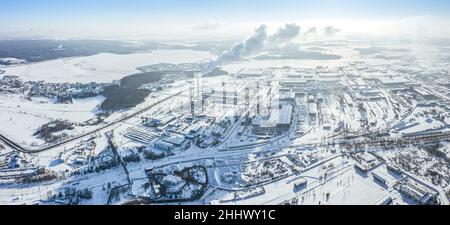 Vorstädtisches Industriegebiet im Winter. Fabrikgebäude, Lagerhäuser und Wärmekraftwerk an einem kalten Wintertag. Luftpanorama. Stockfoto