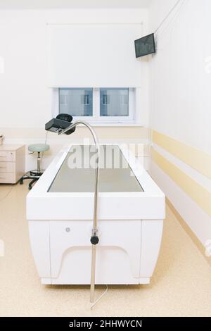 Massageliege im Klinikraum. Rehabilitationszentrum des Krankenhauses. Moderne medizinische Geräte, Konzept der präventiven Medizin. Modernes Krankenhauslabor Stockfoto