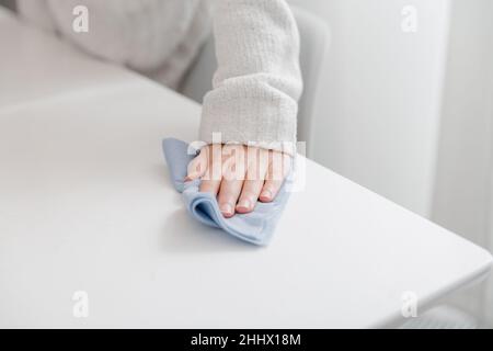 Reinigung des Tisches mit einem blauen Mikrofasertuch. Desinfizieren Sie Oberflächen Prävention in Krankenhäusern und öffentlichen Räumen gegen Coronavirus. Frau Hand mit nass Stockfoto