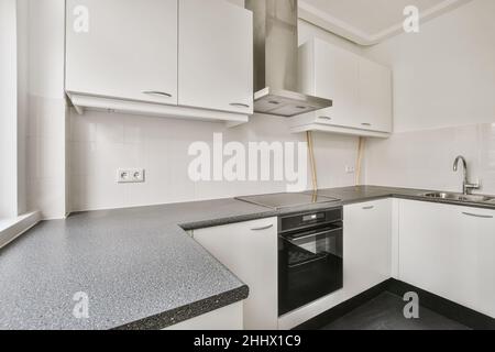 Charmantes Design einer kleinen Küche mit einer schwarzen Arbeitsplatte in einem stilvollen Haus Stockfoto