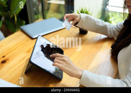 Eine Frau gibt eine Kreditkartennummer in einer Internet-Banking-Anwendung auf einem Tablet-Computer ein, Nahaufnahme Stockfoto
