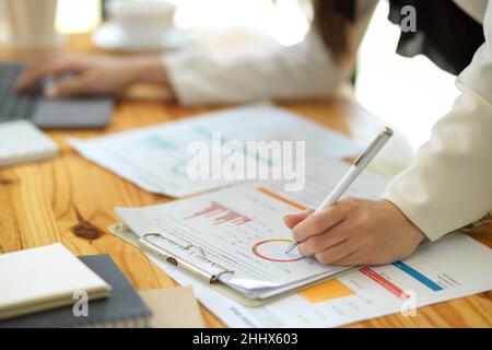 Eine beschnittene, Nahaufnahme-Bild, Eine Unternehmerin schaut sich um und überprüft den Finanzbericht. Stockfoto