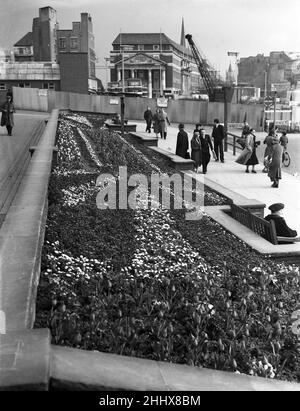 Shopper genießen die Frühlingssonne und die Blumenbeete vor der Holy Trinity Church, Coventry City Centre, West Midlands, England, um 1953. Auch abgebildet, im Hintergrund, Bauarbeiten an der Broads Street. Stockfoto