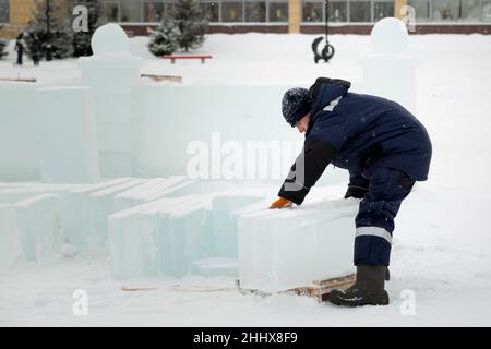 Mann lädt Eisplatten auf Holzschlitten Stockfoto