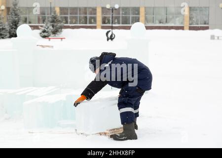 Mann lädt Eisplatten auf Holzschlitten Stockfoto