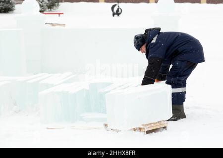 Mann lädt Eisplatten auf Holzschlitten Stockfoto