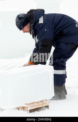 Mann lädt Eisplatten auf Holzschlitten Stockfoto