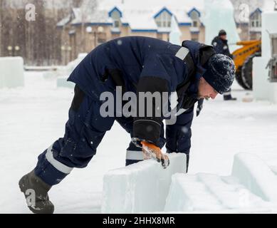 Mann lädt Eisplatten auf Holzschlitten Stockfoto