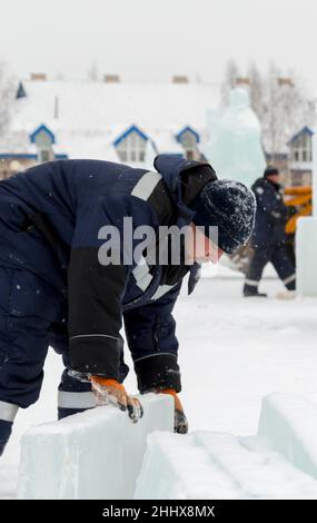 Mann lädt Eisplatten auf Holzschlitten Stockfoto