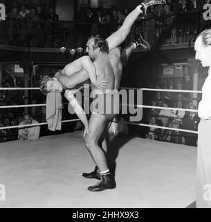 Primo Carnera, Schauspieler und professioneller Wrestler, ebenfalls ein ehemaliger Profi-Boxer, fotografierte Drehszenen für den neuen Film A Kid for Two Farthings in den Shepperton Studios, Surrey, England, 13th. September 1954. Das Set ist eine Darstellung eines Wrestling-Rings in East London. Er spielt Python Macklin, gegenüber Joe Robinson, dem World Wrestling Champion von 1951 und aktuellen Judo-Weltmeister, als Sam Heppner. Stockfoto