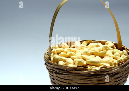 Geröstete gesalzene rohe Cashewnüsse in einer Holzschüssel auf einem rustikalen Tisch, gesunder vegetarischer Snack, Anacardium occidentale, Cashews auf weißem Hintergrund, Cashews. Stockfoto