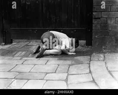 England V Australien 1954 4th Testspiel Headingley Leeds. Ein kleiner Junge vor dem Yorkshire Cricket Club in Headingley wirft einen kurzen Blick unter die großen Holztüren, um zu sehen, wie sich England im vierten Test gegen Australien zeigt. 23rd. Juli 1954 Stockfoto