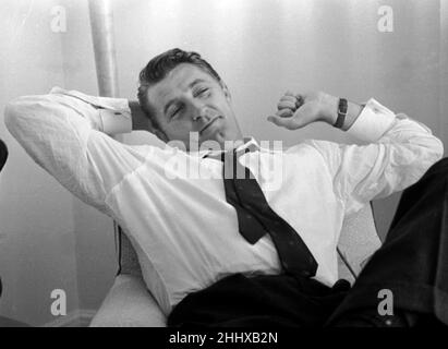 Der amerikanische Schauspieler Robert Mitchum hielt sich am 1955. Juli bei einem Presseinterview in London mit den Armen hinter dem Kopf Stockfoto