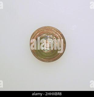 Glas-Spindel-Whorl ca. 1st–2nd. Jahrhundert n. Chr. Roman Durchscheinend hellgelb grün, mit Spuren in gleicher Farbe.hoher, gewölbter Körper; leicht konvexer Boden; senkrechtes Loch unten größer.Spiralpfad auf der Oberseite und Unterseite. Intakt; Nadelstich Blasen; etwas dullend und cremig schillernde Verwitterung.. Spindelwelle aus Glas Roman. Ca. 1st–2nd Jahrhundert n. Chr. Glas; stabförmig und gewickelt. Früh bis mittelkaiserlich. Glas Stockfoto