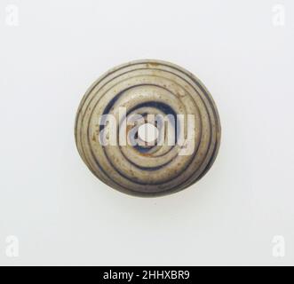 Glas-Spindel-Whorl ca. 1st–2nd. Jahrhundert n. Chr. Roman Durchscheinendes Kobaltblau, mit opaker weißer Spur.gewölbter Körper, in der Mitte abgeflacht; flacher Boden; vertikales Loch.Pfad, der von der Mitte bis zum äußeren Rand spiralförmig auf die obere Oberfläche aufgetragen wird.intakt; etwas stumpfend, Lochfraß und schwache Verwitterung.hergestellt durch gewundene Spur in einer Spirale um den Stab. Spindelwelle aus Glas Roman. Ca. 1st–2nd Jahrhundert n. Chr. Glas; stabförmig und gewickelt. Früh bis mittelkaiserlich. Glas Stockfoto