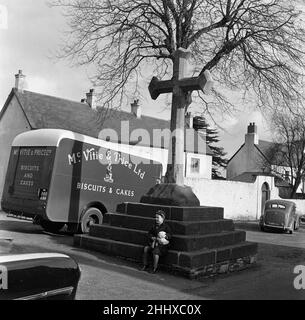 Ein kleiner Junge sitzt auf den Stufen des City Cross, Llandaff Cathedral, South Wales. 1st. März 1954. Stockfoto