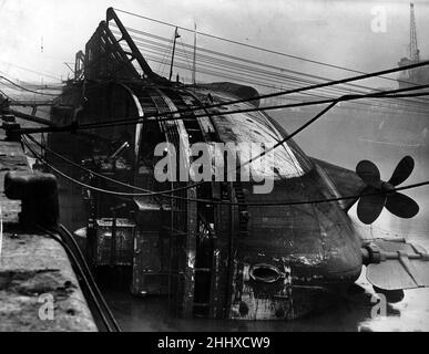 Arbeiter konnten sich auf die unteren Regionen des ausgebrannten Canadian Pacific Liner Empress of Canada konzentrieren, im Gladstone Dock, Liverpool, als das Wasser auf einen Stand von 24ft abgesenkt wurde. Das Bild zeigt Falschleute, die an Stativen auf der Schiffsseite befestigt sind, um sie leicht zu richten. 16th. Februar 1954. Stockfoto