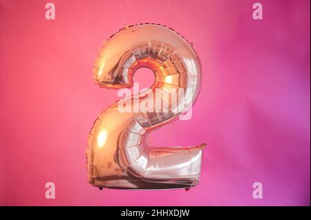 Berlin, Deutschland. 14th Januar 2022. ABBILDUNG - Ein goldener Ballon in Form der Zahl 2 hängt vor einem rosa Hintergrund. (Posed Scene) Quelle: Annette Riedl/dpa/Alamy Live News Stockfoto