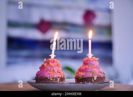 Berlin, Deutschland. 12th Januar 2022. ABBILDUNG - zwei Cupcakes mit brennenden Kerzen stehen auf einem Tisch. (Posierte Szene) die '2': Symbol für Gegensätze, aber auch für romantische Liebe. Für einige ist es eine glückliche Zahl, für andere nur eine von zehn Ziffern. Sie ist allgegenwärtig. (To dpa: 'Die Nummer zwei: Mathematisch, gesellig, rückwärts') Quelle: Annette Riedl/dpa/Alamy Live News Stockfoto
