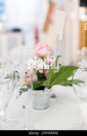 Eine vertikale Aufnahme von einigen Blumen in einem Topf auf einem für die Hochzeit vorbereiteten Tisch Stockfoto
