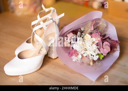 Die Brautschuhe mit einem Hochzeitsstrauß auf dem Boden Stockfoto