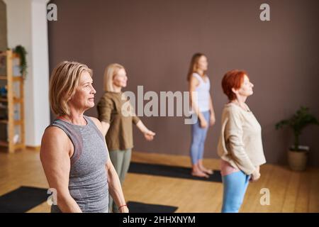 Eine Gruppe von Frauen im aktiven Ohr, die auf Matten stehen und Entspannungsübungen während des Trainings im Fitnessstudio oder Fitnesscenter machen Stockfoto