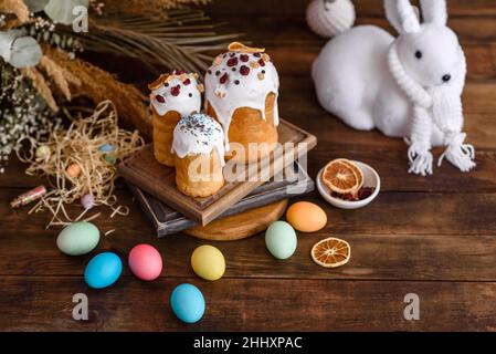 Osterkuchen und Eier in verschiedenen Farben mit Osterhase auf Holzhintergrund gemalt Stockfoto