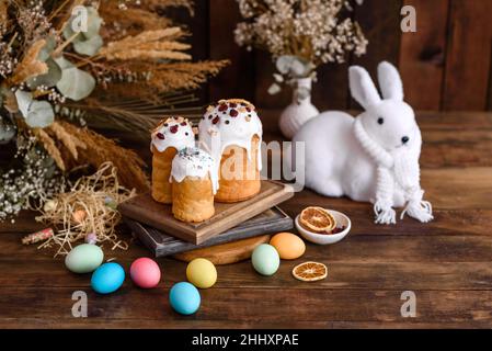 Osterkuchen und Eier in verschiedenen Farben mit Osterhase auf Holzhintergrund gemalt Stockfoto