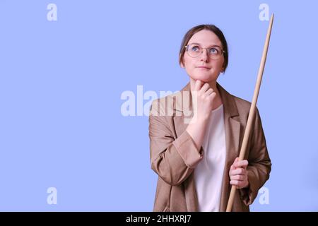 Nachdenkliche Lehrerin mit Zeiger auf blauem Hintergrund, Kopierraum Stockfoto