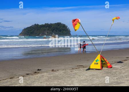Der Strand am Mount Maunganui, Neuseeland, mit gekreuzten Surf-Rettungsschwimmerfahnen, die die Menschen davor warnen, im rauen Wasser zu schwimmen Stockfoto