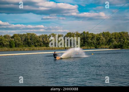 Erfahrener Wakeboarder gleitet auf dem Wasser mit Bordkante, was Spritzer erzeugt Stockfoto