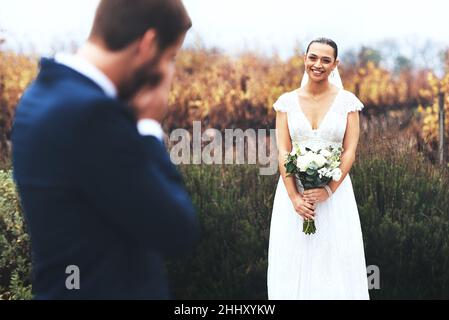 Ihre Schönheit bringt ihn zu Tränen. Aufnahme eines weinenden Bräutigams, während er seine schöne Braut an ihrem Hochzeitstag ansah. Stockfoto