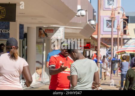 WINDHOEK NAMIBIA - MAI 10 2018; Menschen in der Stadt Straße mit zwei lokalen Männern im Gespräch. Stockfoto