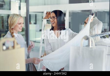 Dieses hier ist mein Bestseller. Aufnahme einer Verkäuferin, die einer jungen Frau in einer Bekleidungsboutique hilft. Stockfoto