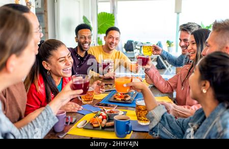 Multirassische Gruppe von Menschen, die in einem Restaurant an der Tischbar sitzen und zusammen ein englisches Brunch-Frühstück genießen, reden und Spaß haben, zu lachen. Freunde Stockfoto