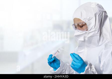 Medizinischer Gesundheitsdienst, NHS-Techniker, der hält, COVID-19 Abstrichbesteck, trägt weiße Schutzanzug-Maskenhandschuhe, Testschlauch für OP NP-Patienten Stockfoto