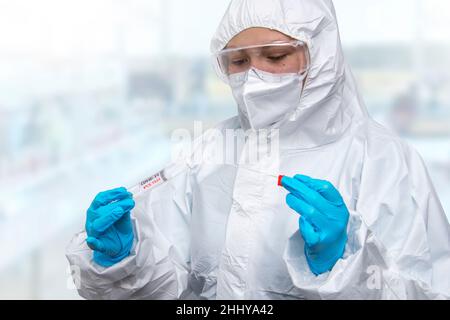 Medizinischer Gesundheitsdienst, NHS-Techniker, der hält, COVID-19 Abstrichbesteck, trägt weiße Schutzanzug-Maskenhandschuhe, Testschlauch für OP NP-Patienten Stockfoto