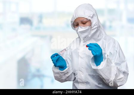 Medizinischer Gesundheitsdienst, NHS-Techniker, der hält, COVID-19 Abstrichbesteck, trägt weiße Schutzanzug-Maskenhandschuhe, Testschlauch für OP NP-Patienten Stockfoto