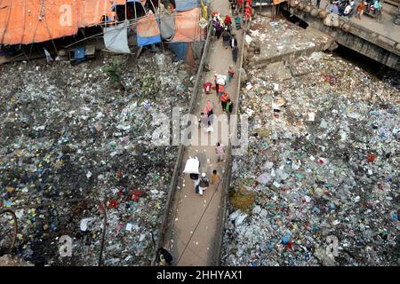 Dhaka, Bangladesch, 25. Januar 2022. Die Menschen gehen über eine Brücke über ein verschmutztes Gebiet, und Kinder gehen über ein verschmutztes Gebiet, während sie Plastikmaterialien sammeln in Dhaka, Bangladesch, 25. Januar 2022. Foto von Habibur Rahman/ABACAPRESS.COM Stockfoto